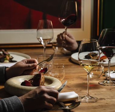 Gostje uživajo v gurmanski večerji z izbranimi vini v prijetnem ambientu restavracije.