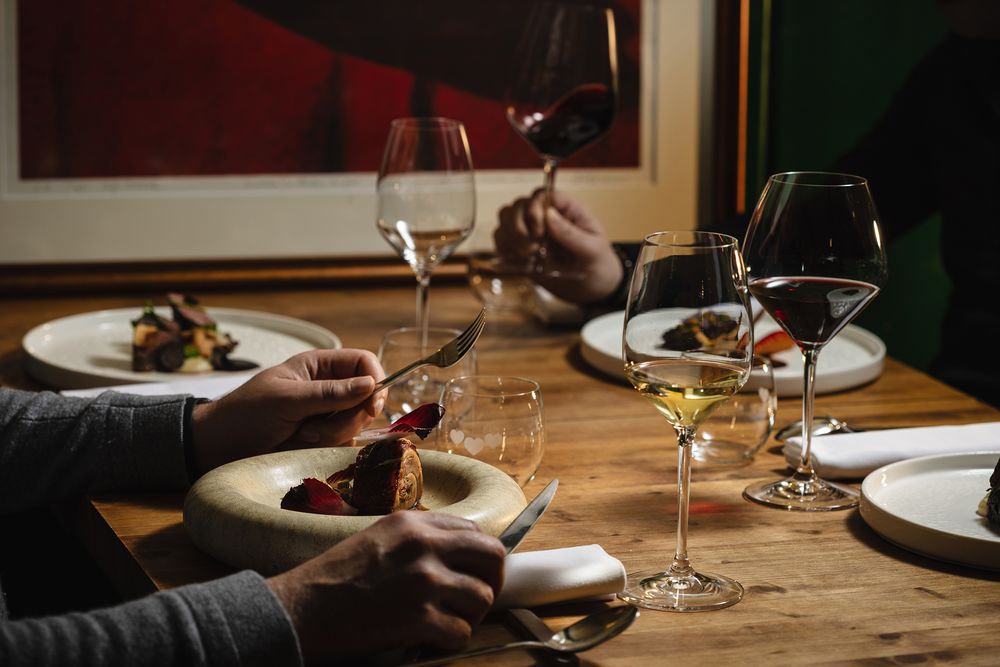 Gostje uživajo v gurmanski večerji z izbranimi vini v prijetnem ambientu restavracije.